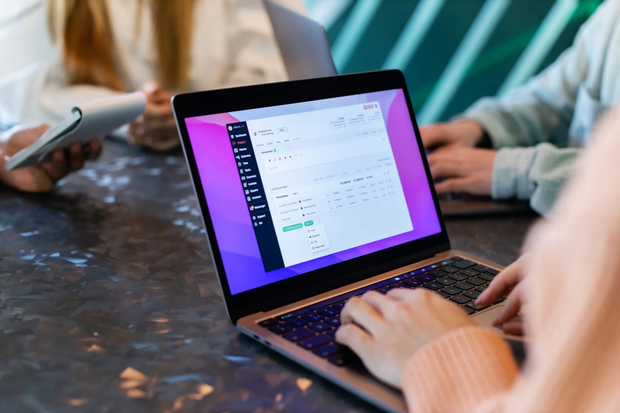 A team working on laptops around a table, one screen showing a web app